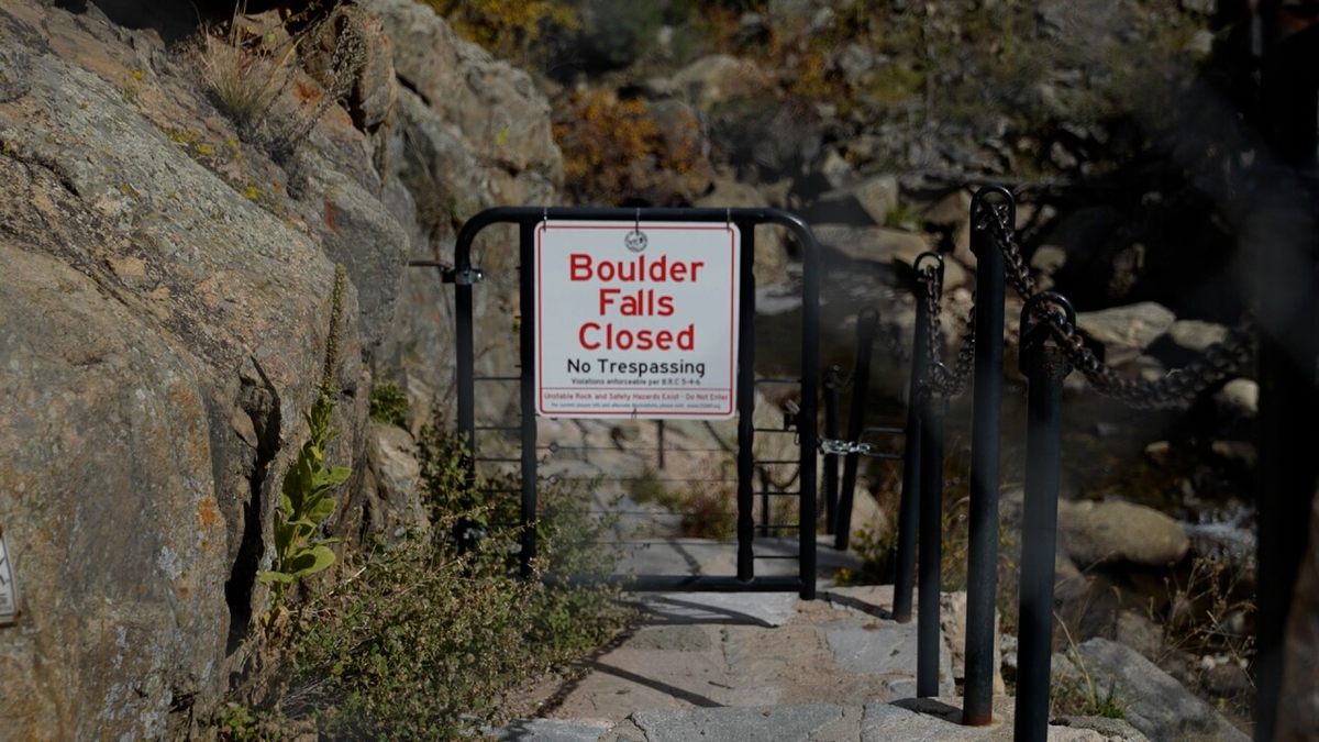 A sign reading Boulder Falls Closed, No Trespassing, across the gated entrance at the pullout.