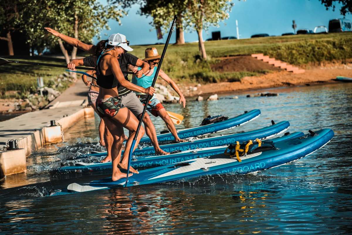 Paddleboards being carried into the water at the Boulder Reservoir swim beach.