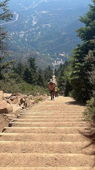 A hiker climbing the rock-step staircase on the Mount Sanitas trail.